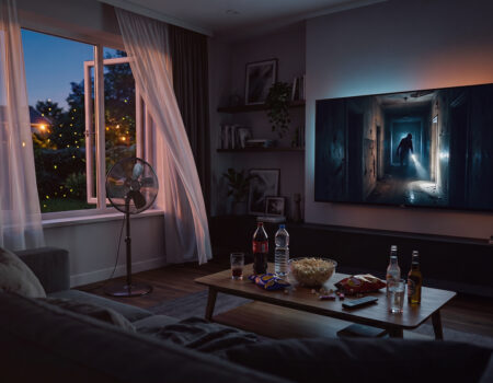 Woonkamer met openstaande ramen, ventilator en een horrorfilm, op de tv